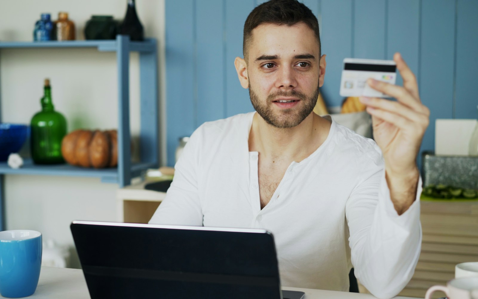 Shopper holding a credit card in front of a laptop