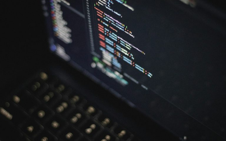 Code on a laptop screen in a dark room